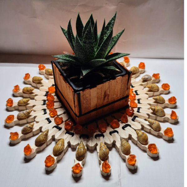 Décoration de table en épingles de bois orné de coquillages et d’éclats plastiques orange transparents et d’un cordon de cuir tressé recouvert d’huile de protection incolore