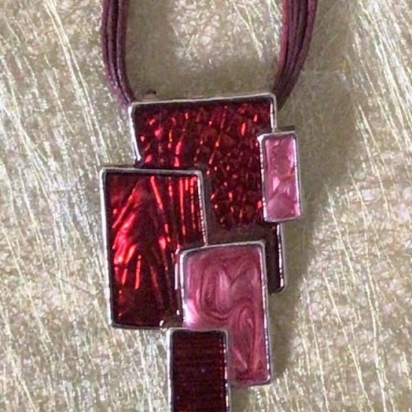 collier en cordons tressés tons rouges, médaille en métal et résines